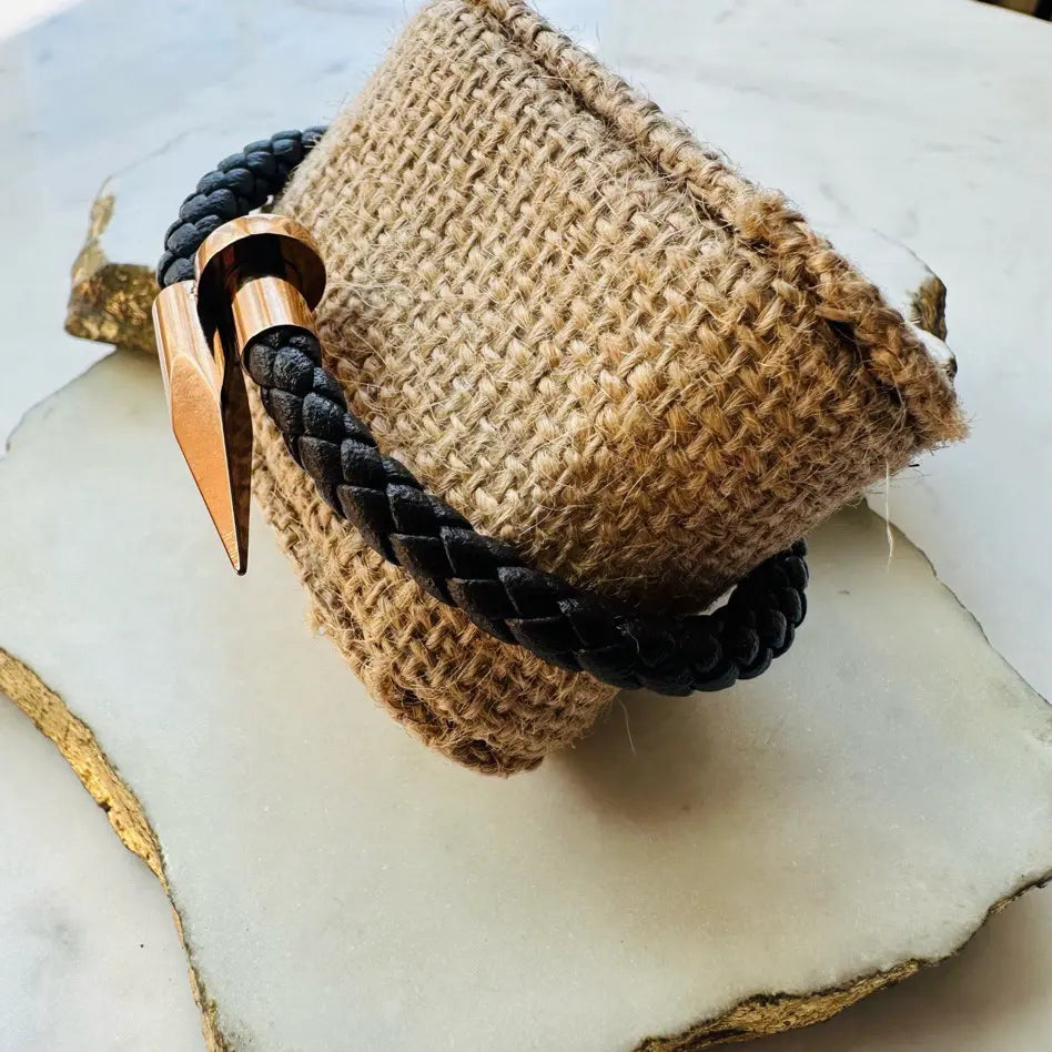 Handmade woven men’s Bracelet with brown braided leather and rose gold clasp on a textured surface