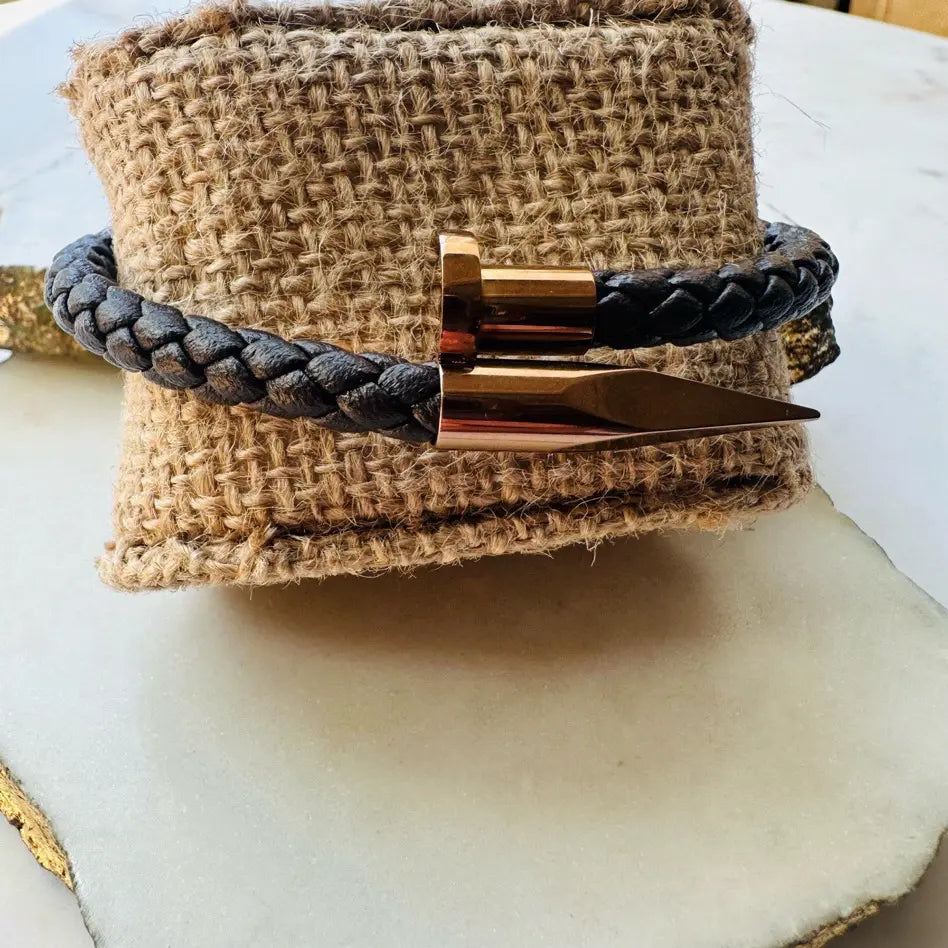 Handmade woven Bracelet with rose gold accents and braided brown leather strap on a textured surface