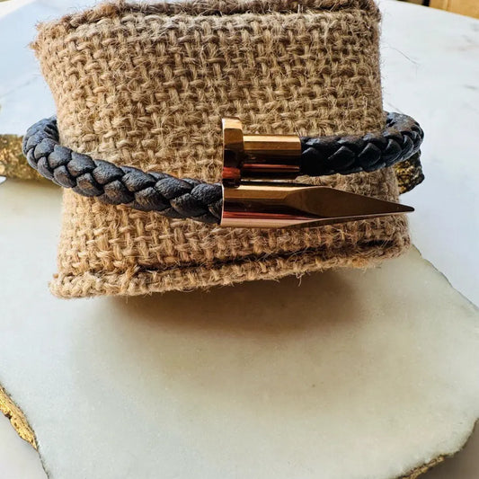 Handmade woven Bracelet with rose gold accents and braided brown leather strap on a textured surface