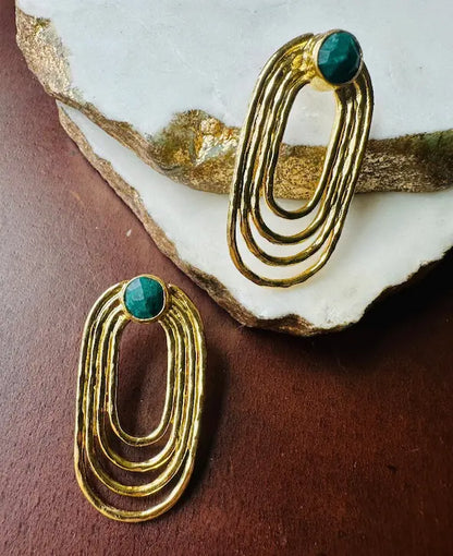 Artisanal Gold-plated paper clip earrings with green gemstones on a textured surface