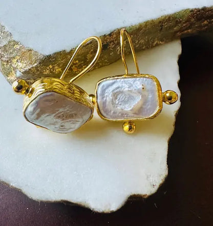 Artisanal sustainable 21 karat gold-plated flat pearl rectangular earrings on white surface 