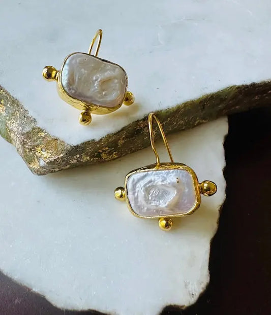 Handmade sustainable 21 karat gold-plated flat pearl rectangle studs with gold embellishings on white marble 