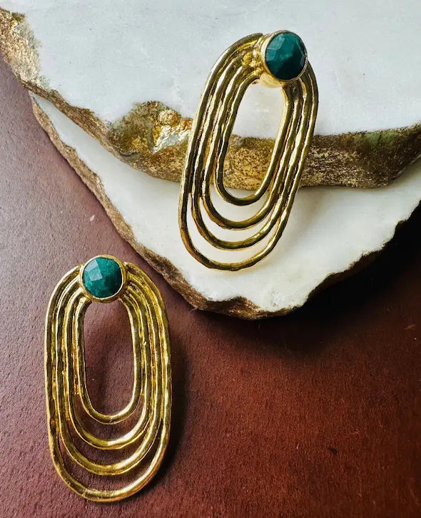 Handmade Gold-plated sustainable paper clip earrings with green gemstones on a textured surface