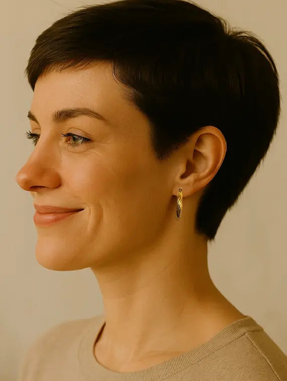 Woman with short dark hair wearing handmade gold-plated everyday stylish hoop  earrings against a neutral background