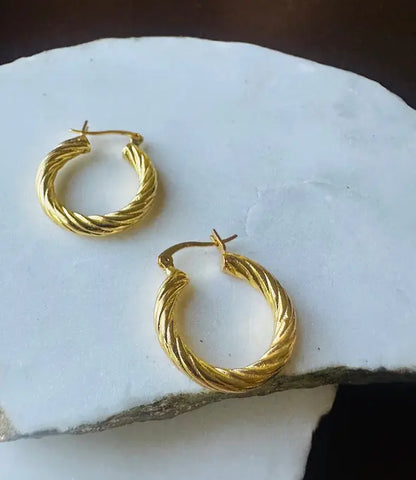 handmade sustainable everyday Gold-plated etched hoop earrings on a white stone surface