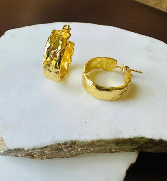 Handmade gold-plated waterproof thick textured Gold hoop earrings with  on a white stone surface