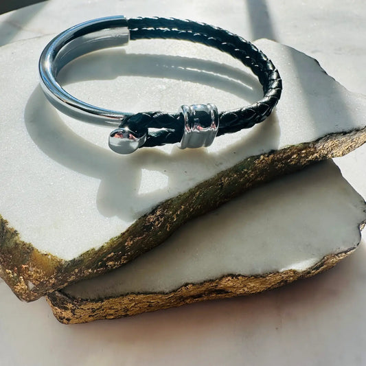 Handmade men’s Black braided leather bracelet with silver clasp on a textured surface