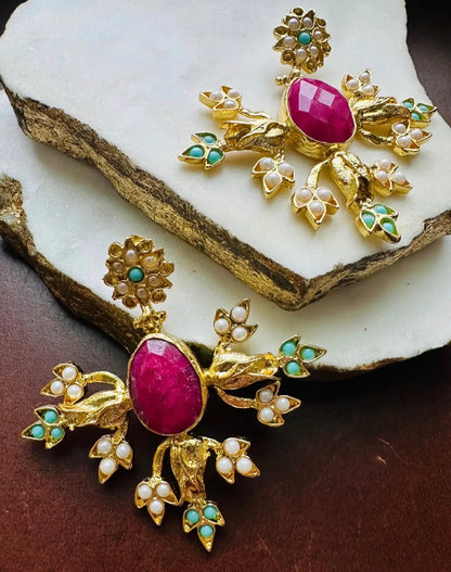 Elegant handmade sustainable Ruby, turquoise, and pearl Indian bridal earrings on a white stone background