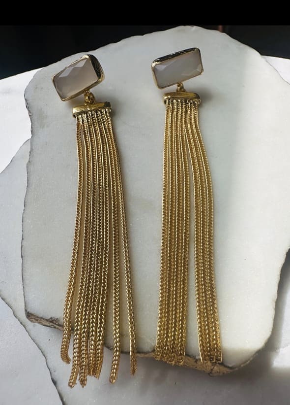 Handmade sustainable Gold-plated snow Quartz and long chain tassel earrings on a white marble surface