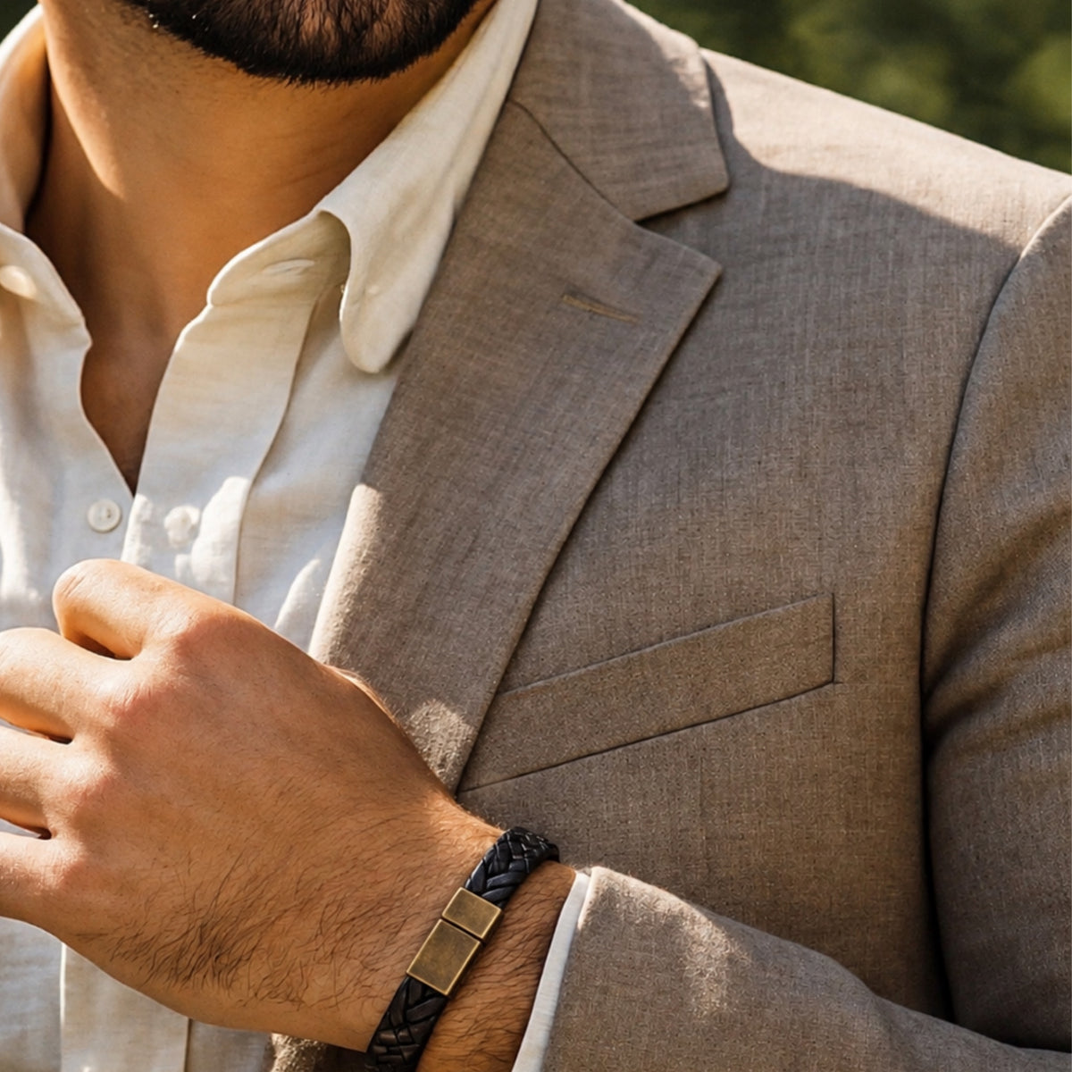 Close up of man in linen suit with bohemian black woven bracelet with antique bronze clasp