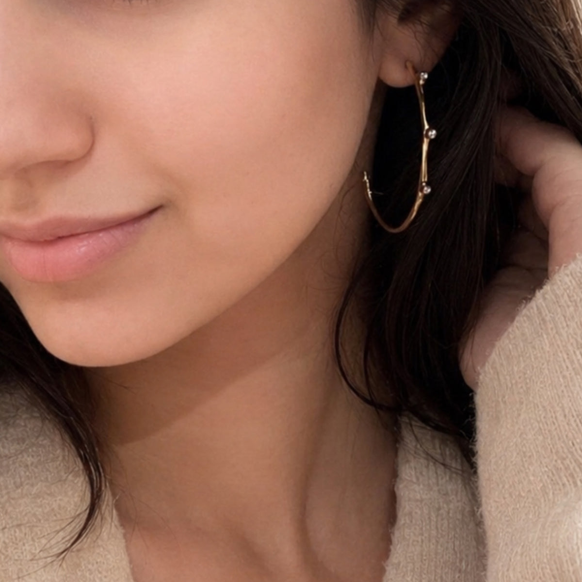 Close up of woman wearing Aritzia beige sweater and textured gold contemporary hoop earrings with cubic zircon