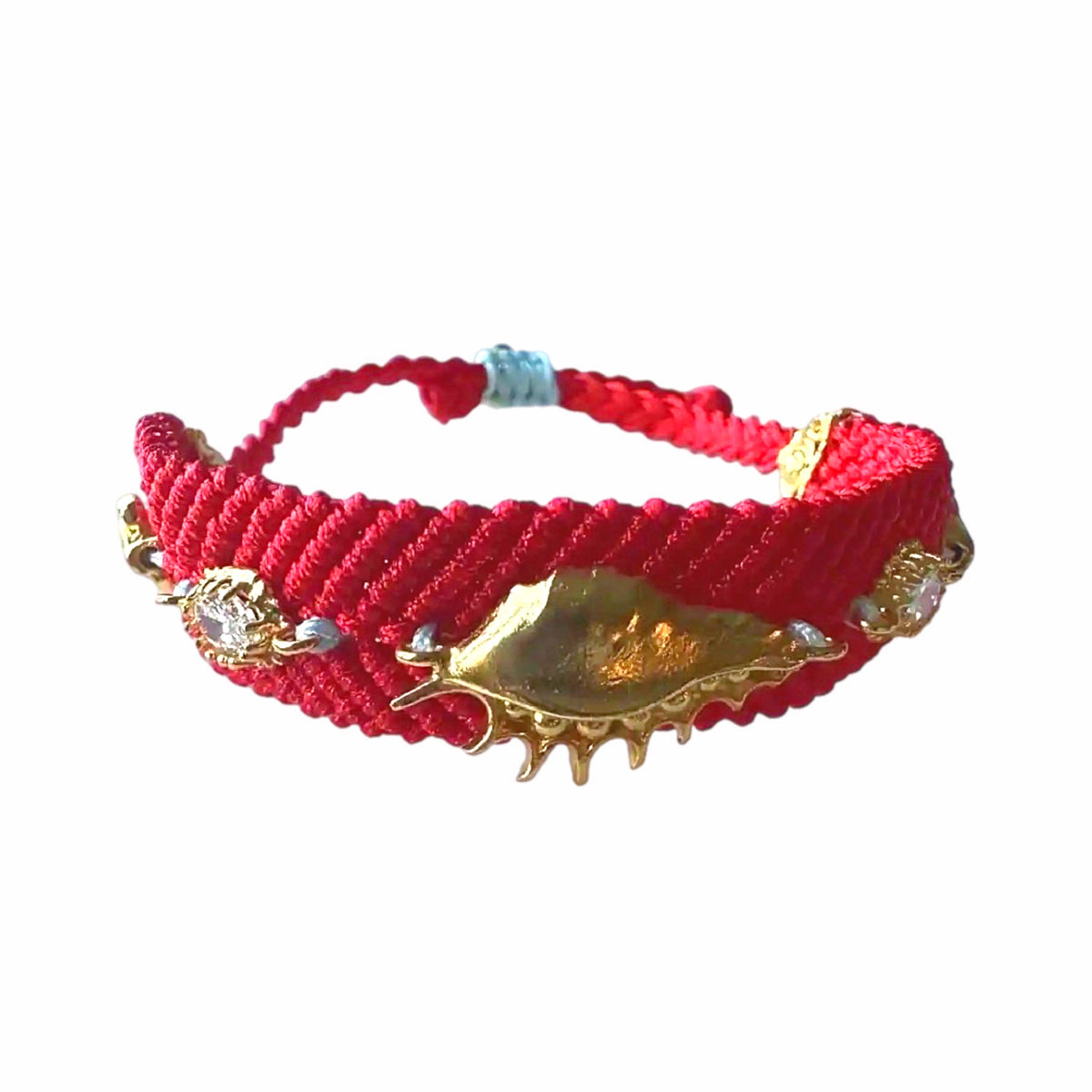 Handmade Red woven bracelet with gold-plated shell and evil eye accents on a white surface