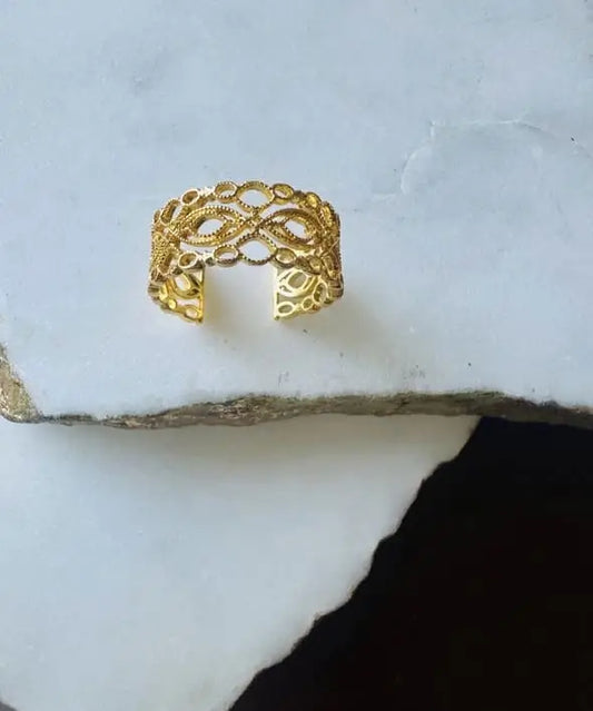 Dainty sustainable artisanal Gold-plated lace ring with intricate design on a textured white surface
