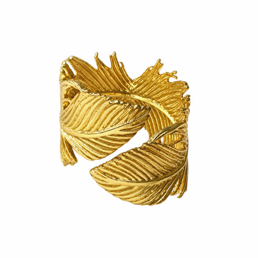 A gold-plated feather-shaped ring with textured, ribbed detailing, shown on a plain white background