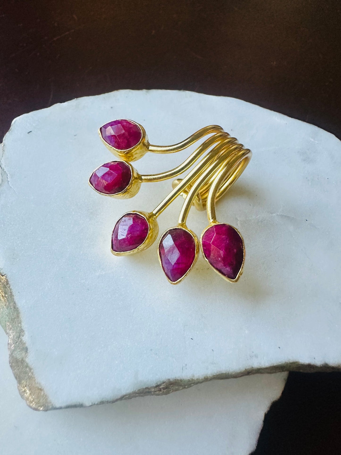 Gold ring with red ruby gemstones on a white stone surface