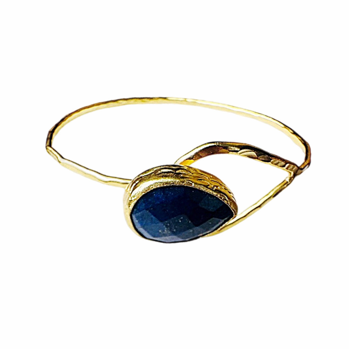 A gold bangle bracelet featuring a teardrop-shaped dark blue lapis gemstone in a textured gold setting, isolated on a white background.
