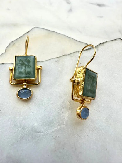 Goldplated contemporary earrings with jade green and blue chalcedony stones on a marble surface