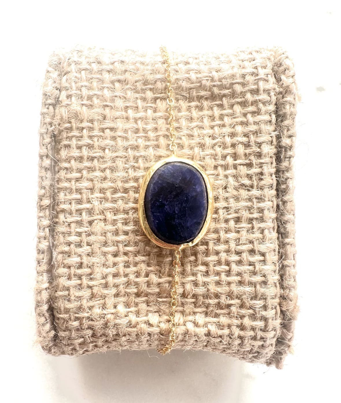 Textured beige cushion with a gold minima bracelet with blue lapis lazuli stone 