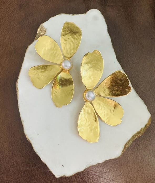 Handmade sustainable Gold-plated contemporary flower-shaped earrings with pearl centers on a white stone background
