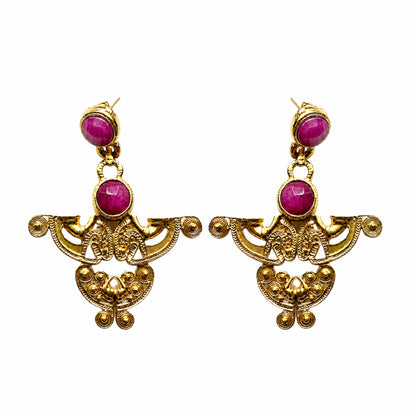 A pair of ornate gold-tone dangle earrings featuring round magenta-pink ruby gemstone accents, displayed against a solid white background.