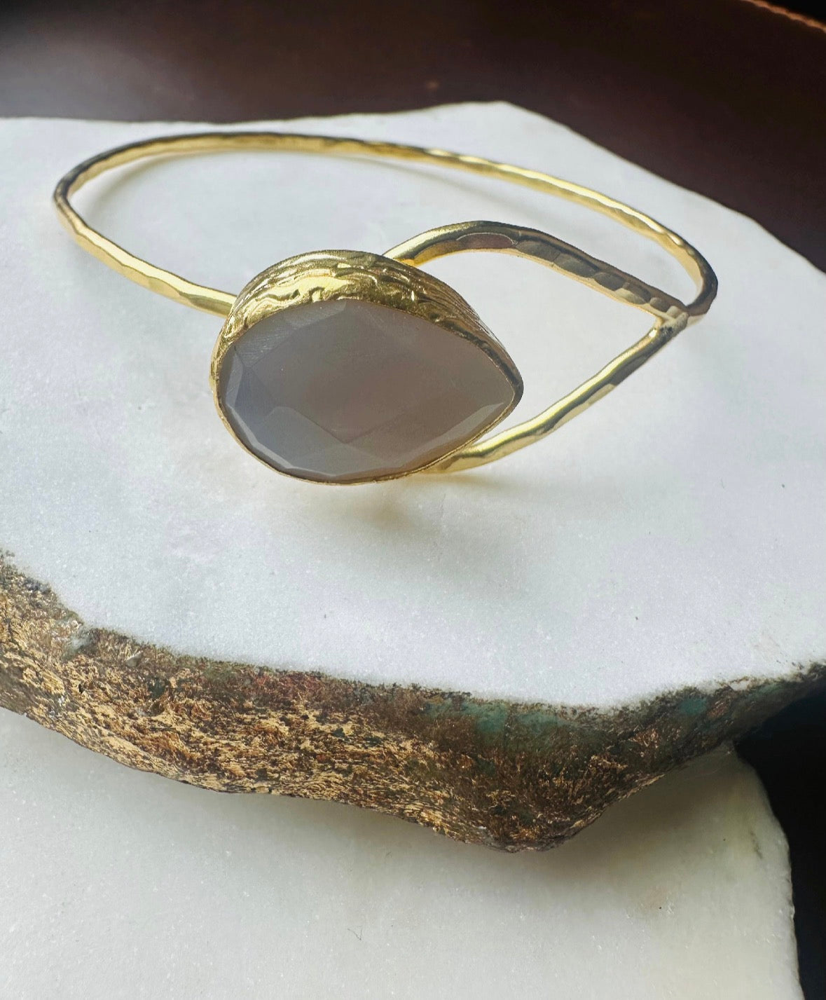 Gold-plated bracelet with a teardrop snow Quartz stone on a white surface