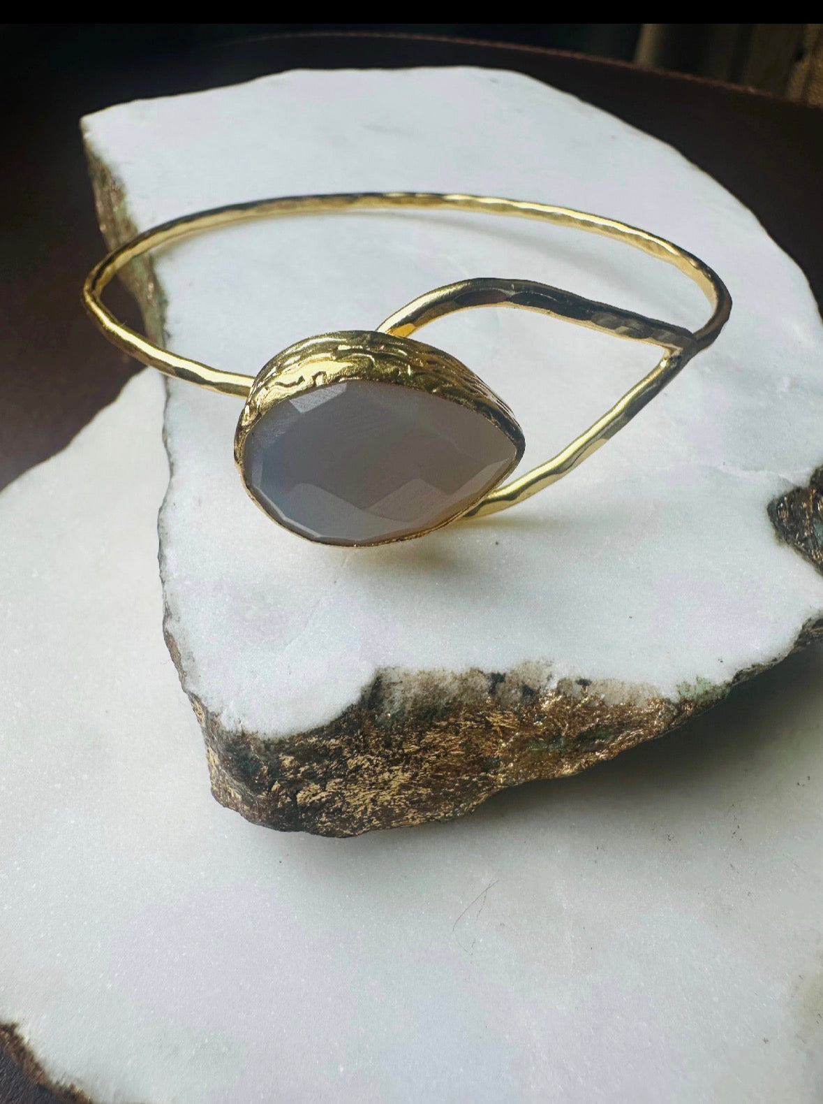 Gold-plated snow Quartz teardrop bracelet with a stone on a white rock