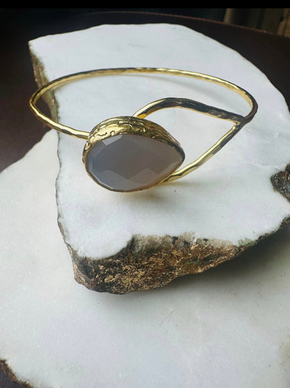Gold-plated snow Quartz teardrop bracelet with a stone on a white rock