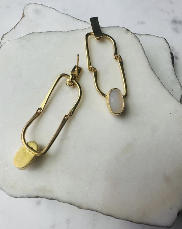 Contemporary handmade flexible Gold-plates hoop earrings with a snow Quartz Gemstone  on a marble surface