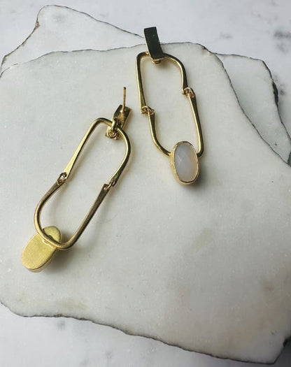 Contemporary handmade flexible Gold-plates hoop earrings with a snow Quartz Gemstone  on a marble surface