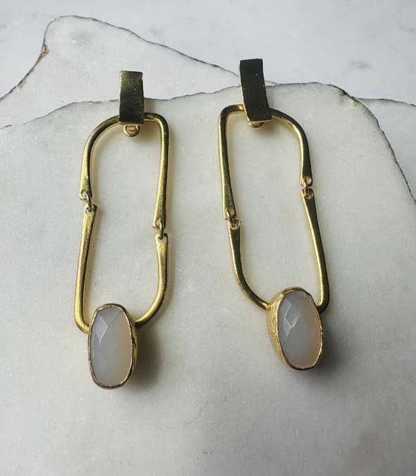 Contemporary handmade sustainable gold-plated flexible link earrings with snow Quartz  placed on marble slabs