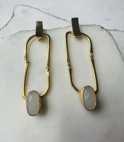 Contemporary handmade sustainable gold-plated flexible link earrings with snow Quartz  placed on marble slabs