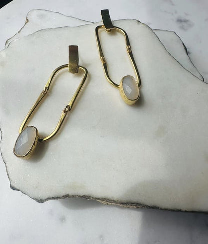 Contemporary Handmade sustainable Gold-plates earrings with snow Quartz stones placed stylistically on a marble surface