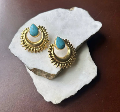 Handmade sustainable bold Gold-plates stud earrings with turquoise stones on a white stone surface