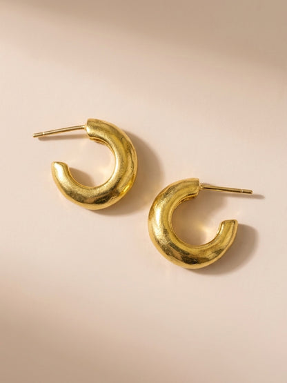 Handmade gold-plated Huggies laying on beige background