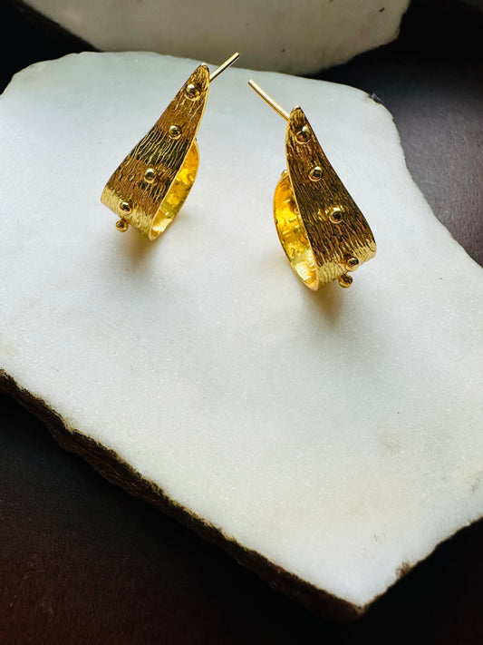 Gold contemporary abstract hoop earrings on a white stone surface