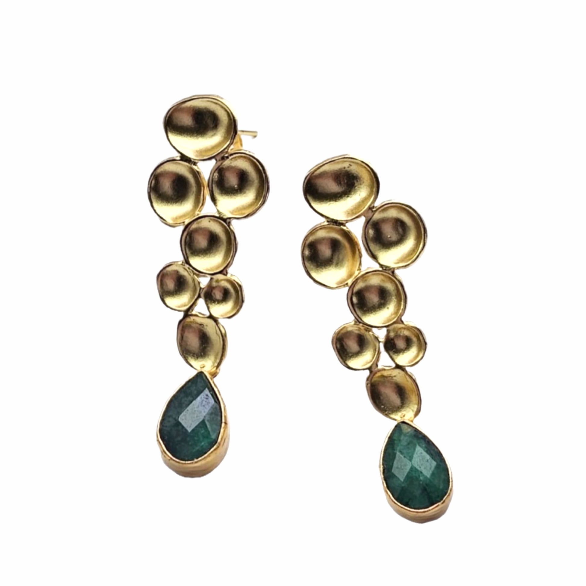 A pair of gold drop earrings featuring  geometric gold metal design and a faceted green teardrop emerald gemstone at the bottom, set against a white background