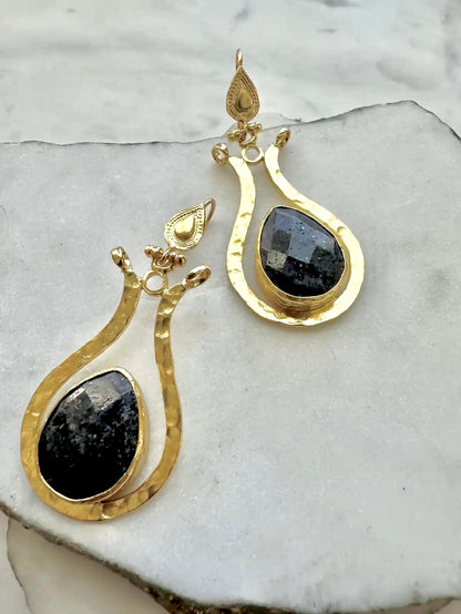 Gold earrings with blue lapiz lazuli stones on a marble surface