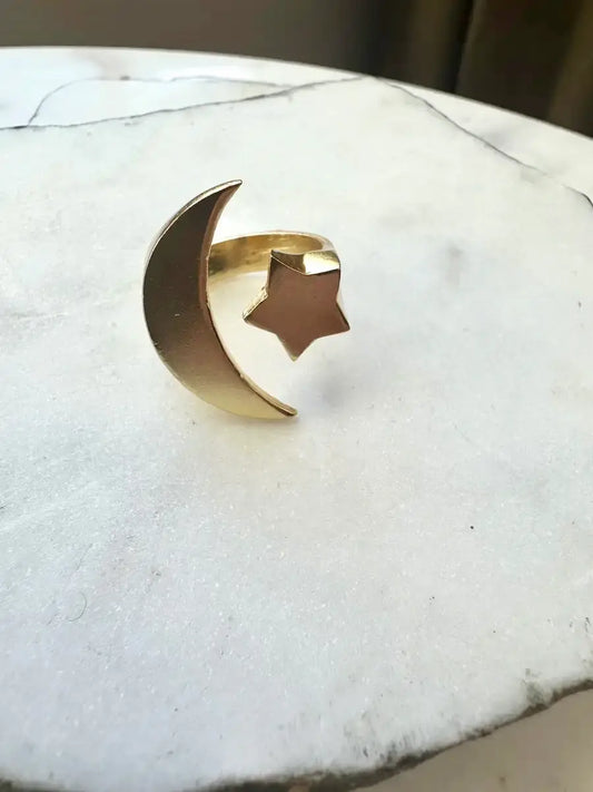 Gold-plated handcrafted ring with moon and star design on a marble surface