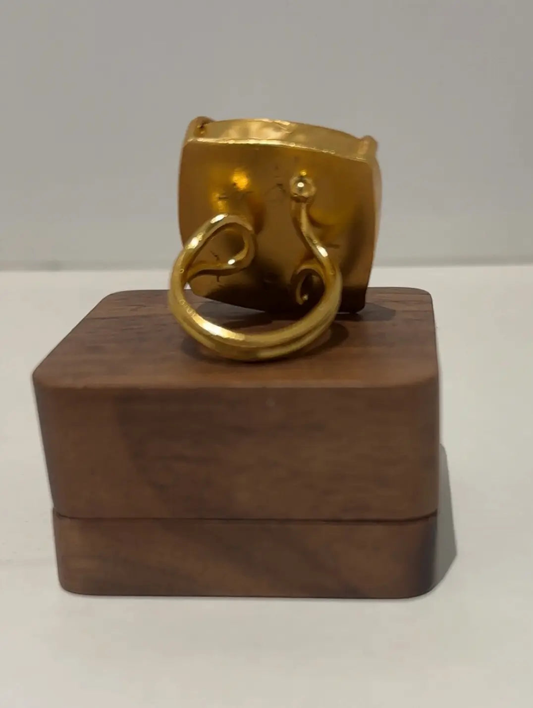 Gold ring on a wooden stand against a gray background