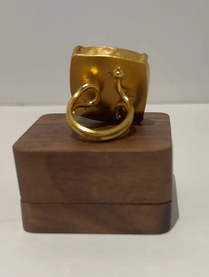 Gold ring on a wooden stand against a gray background