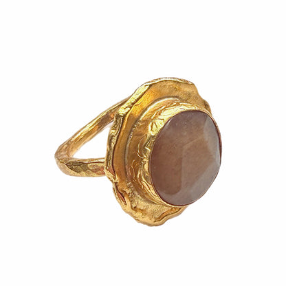 A handmade gold-plated cocktail gemstone ring with an orange quartz stone, shown on a plain white background in side angle