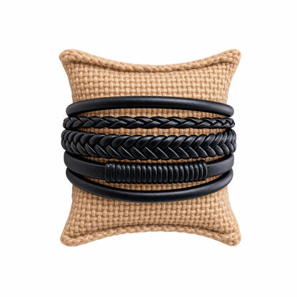 Handmade men’s rugged boho multi-strand braided black leather cuff bracelet on a tan jute jewelry pillow 