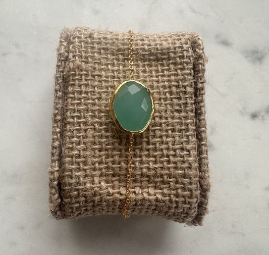 Minimal handmade bracelet with a aqua chalcedony gemstone on a textured fabric surface