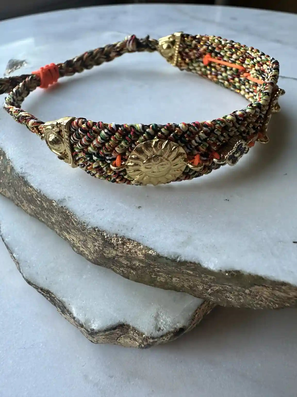 Orange and blue handmade woven Bracelet with gold charm and zircon multicolor on a marble display