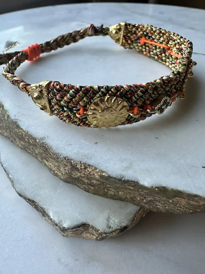 Orange and blue handmade woven Bracelet with gold charm and zircon multicolor on a marble display