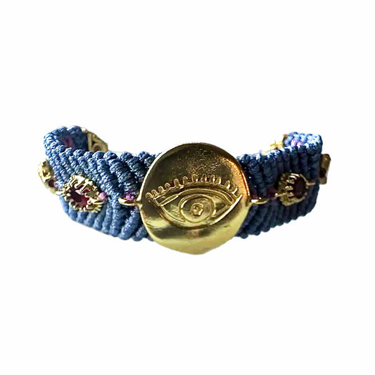 Slate gray woven cord bracelet with gold-played evil eye charm and zircon on a white surface