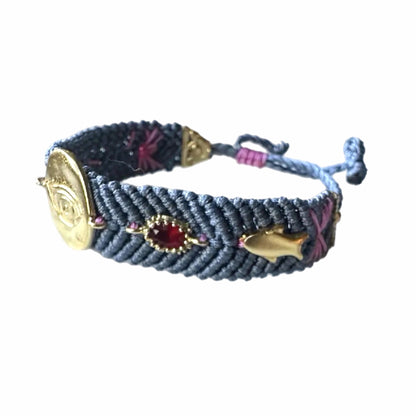 Slate gray handmade woven Bracelet with gold-plated evil eye charm and zircon crystals on a white backdrop 