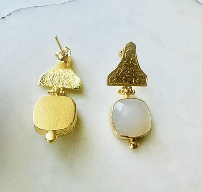 Handmade sustainable gold-plated snow Quartz Etruscan drop earrings against white background with one faced down 