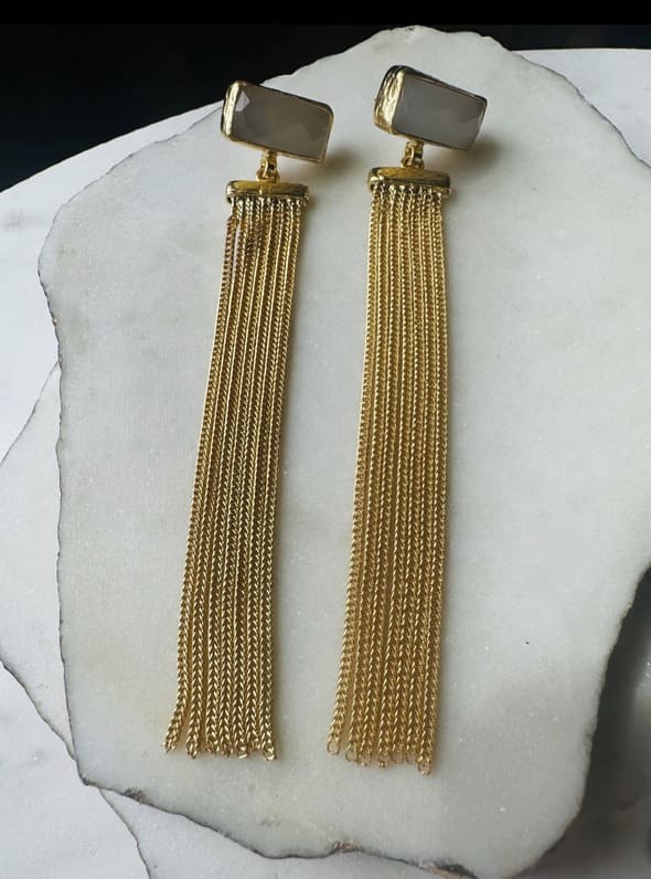 Artisanal sustainable Gold-plated long chain tassel earrings with snow Quartz on a white stone surface