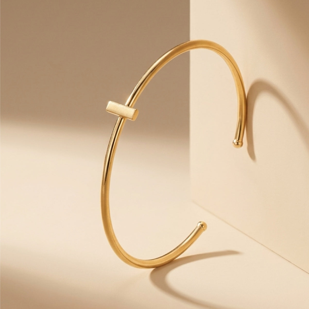 Dainty stackable Gold-plated bracelet with minimal bar on a beige surface 